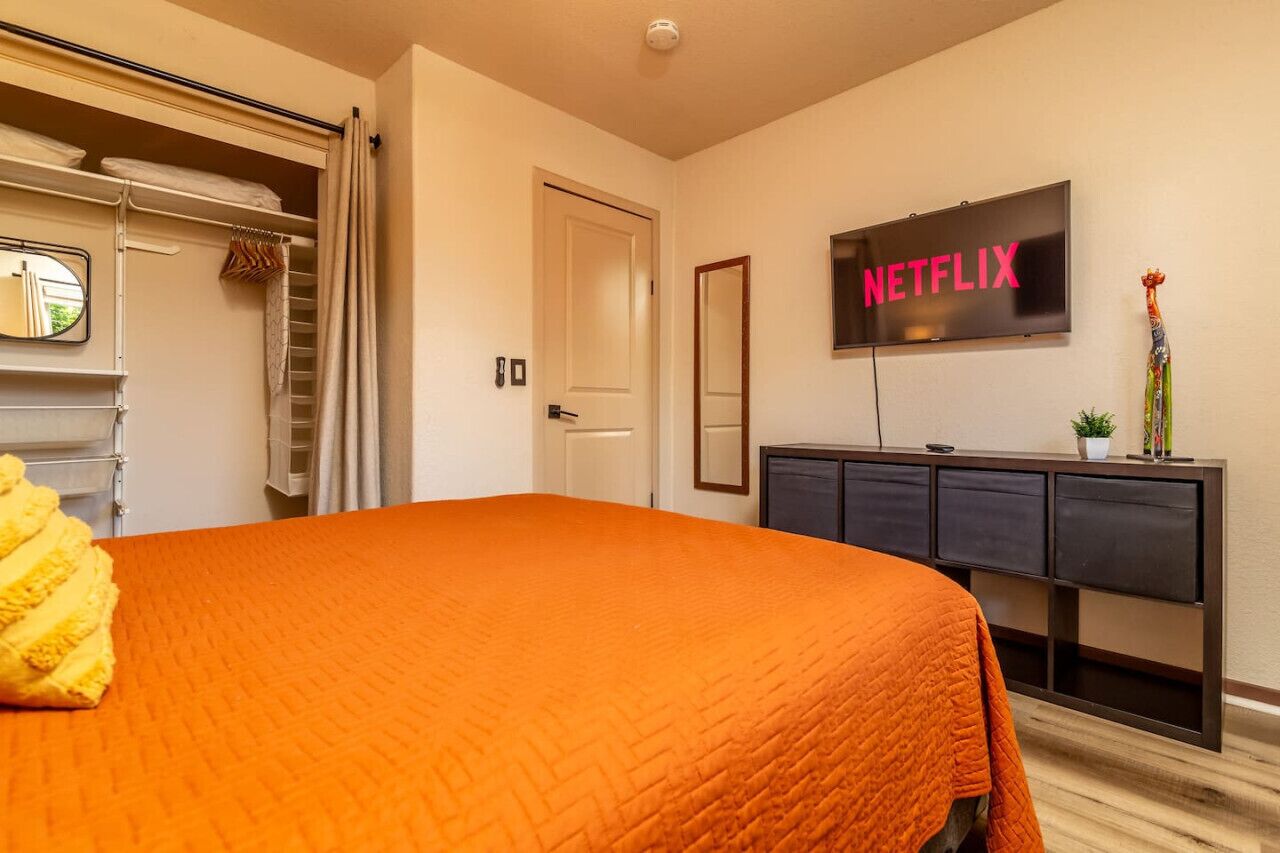 A hotel room with a bed, a TV mounted on the wall, a wardrobe, and a door.