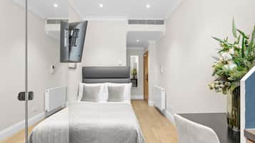 Ein modernes Hotelzimmer mit einem großen Bett, einem Schreibtisch und einer Blumenvase.
