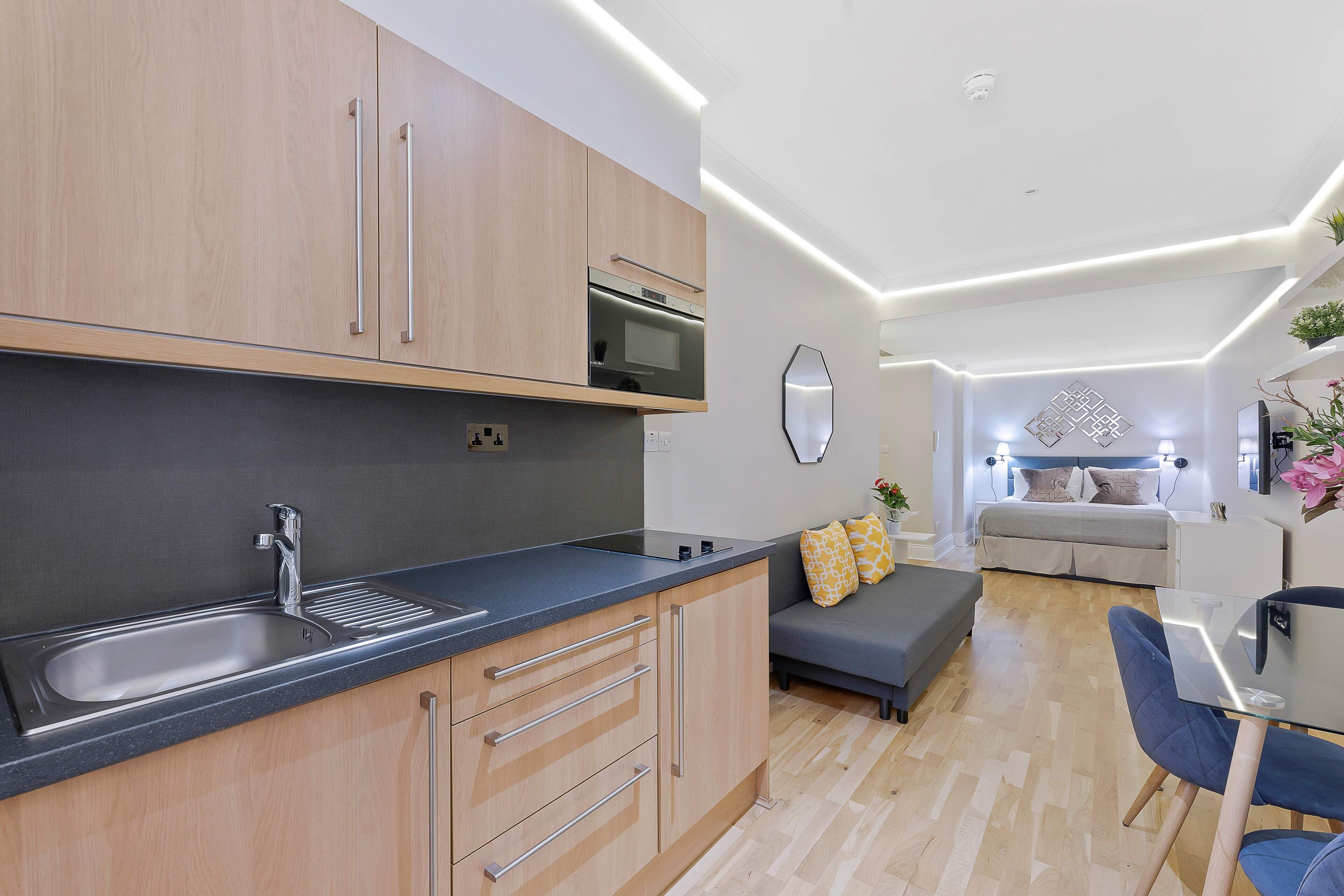 A modern kitchen with a built-in oven, a sink, and wooden cabinets.