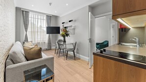 A modern living room with a sofa, TV, and dining area. - Cleveland Residences Russell Square (London)