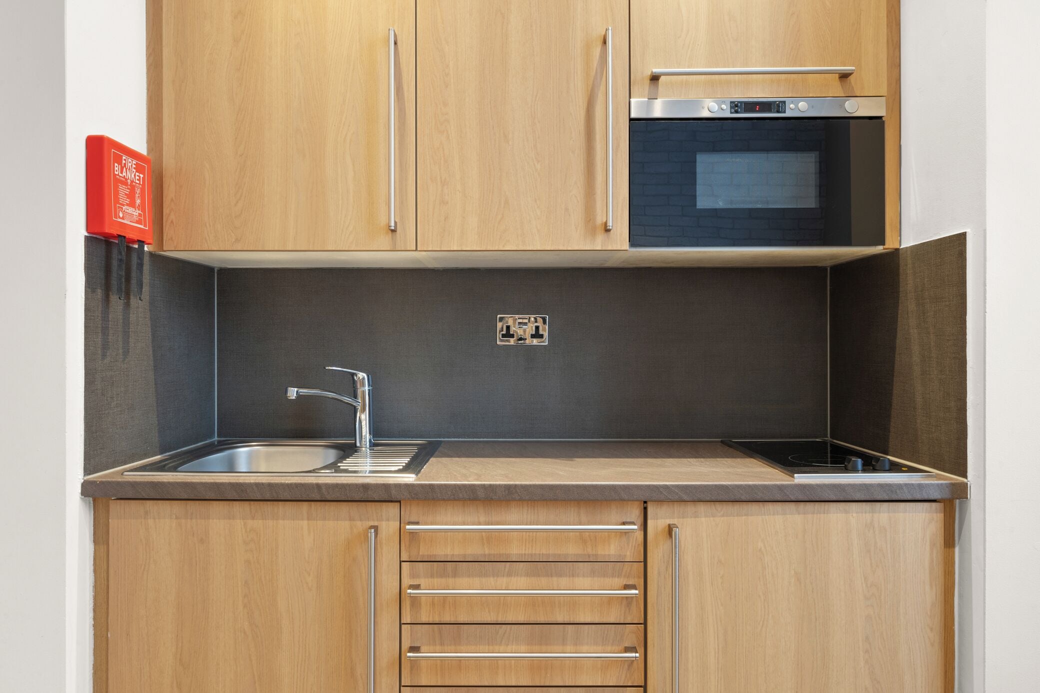 Eine moderne Küche mit Holzausstattung, einer Edelstahlspüle und einem eingebauten Backofen.