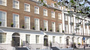 A row of traditional brick townhouses with white facades, multiple windows, and a gated entrance. - Cleveland Residences Russell Square (London)