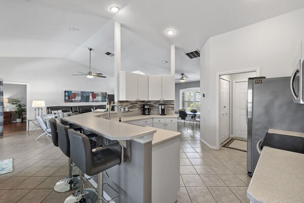 A modern kitchen with a central island, stainless steel appliances, and a dining area with bar stools.