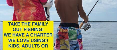 A family on a boat with a fishing rod, a charter boat, and a calm sea.