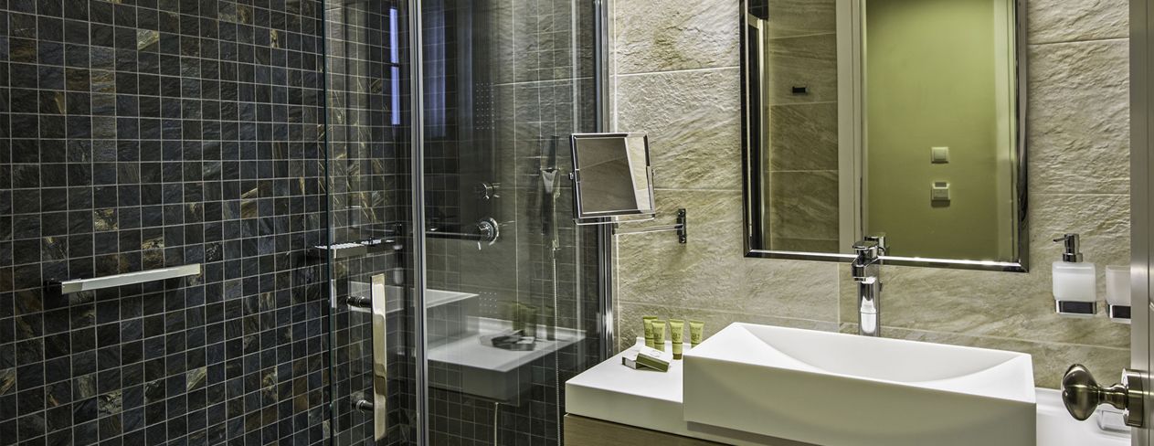 A modern bathroom with a glass shower enclosure, a white sink, and a mirror above the sink.