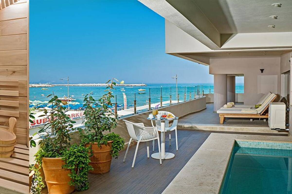 A wooden sauna and a poolside area with a view of the sea.