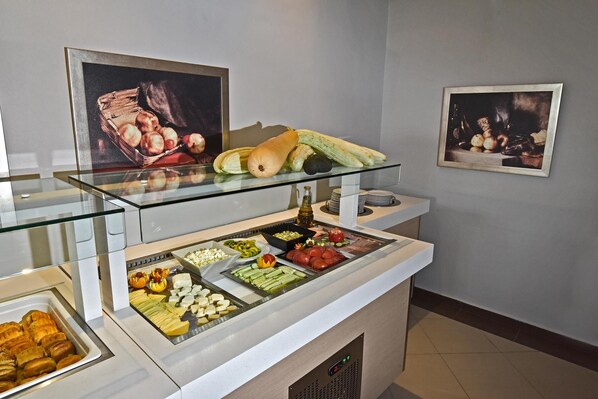 A buffet with various food items and two framed paintings on the wall. - Swell Boutique Hotel (Rethymno)