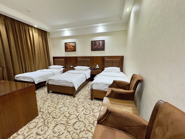 A hotel room with four beds, a desk, a chair, and a carpeted floor. - Sultan (Qarshi)