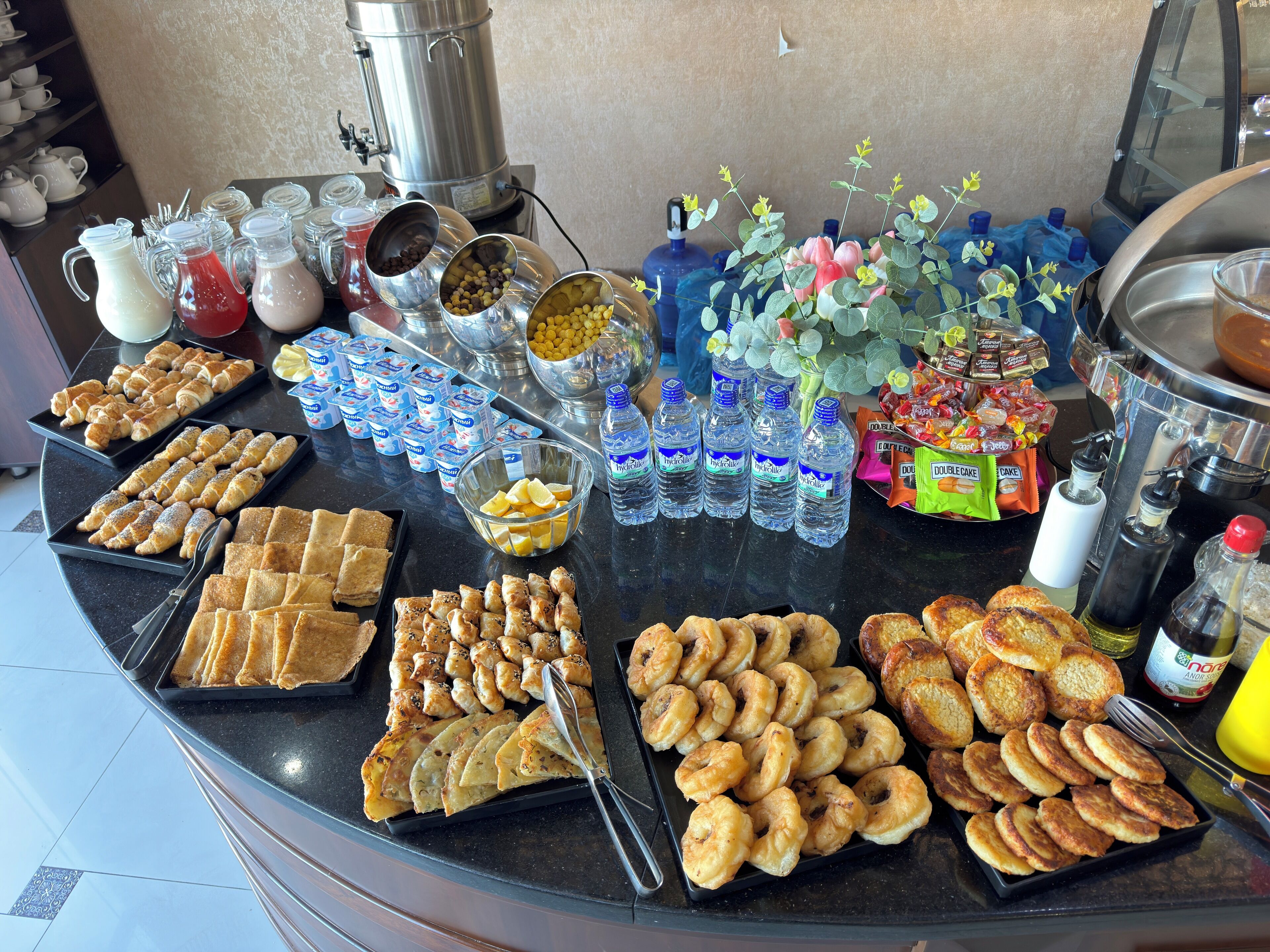 Een ontbijtbuffet met diverse gerechten, waaronder gebak, fruit en drankjes.