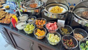 A buffet with various food items including fruits, vegetables, and prepared dishes. - Sultan (Qarshi)