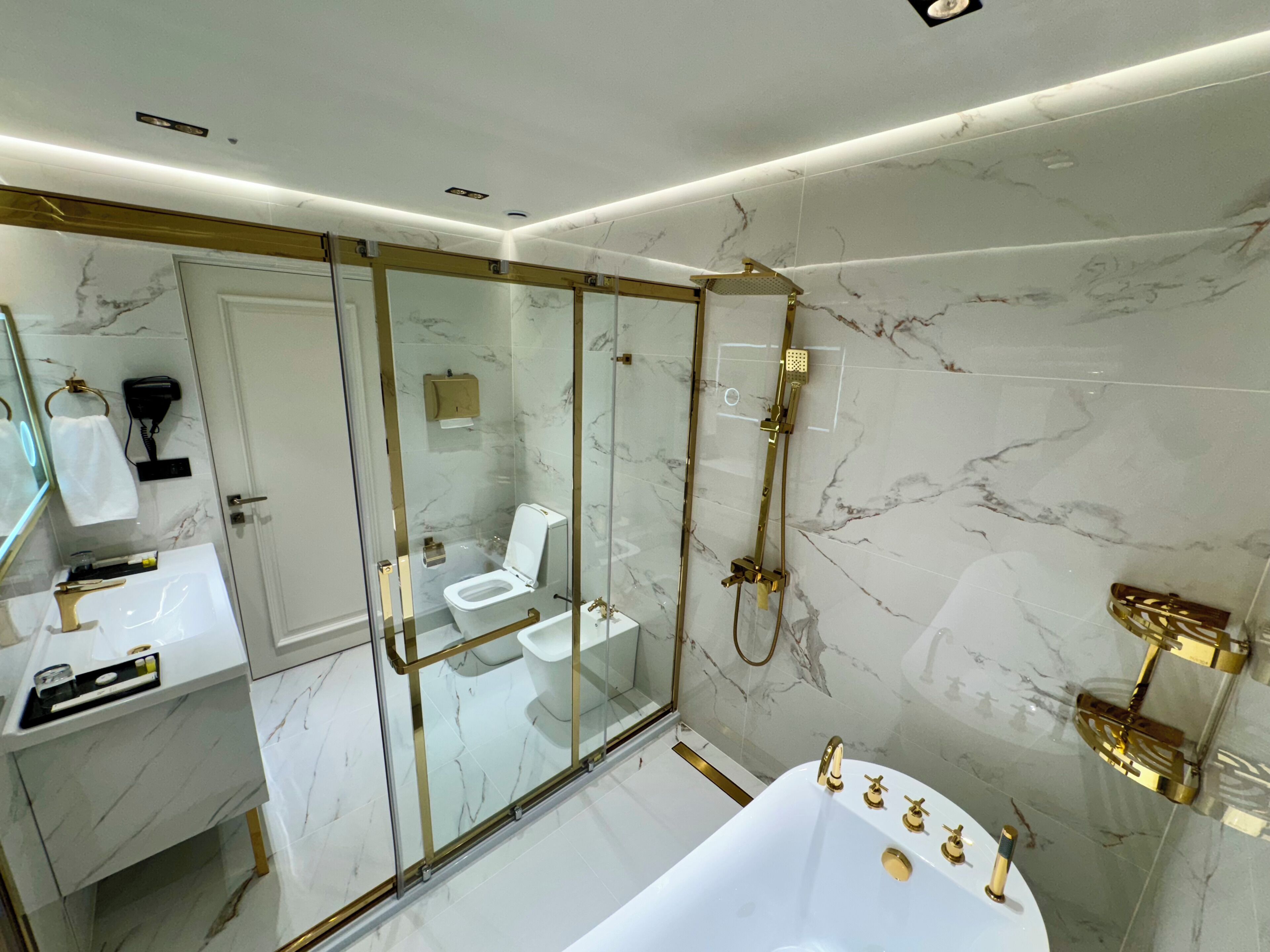 A modern bathroom with a glass-enclosed shower, a white bathtub, and a vanity with a mirror.