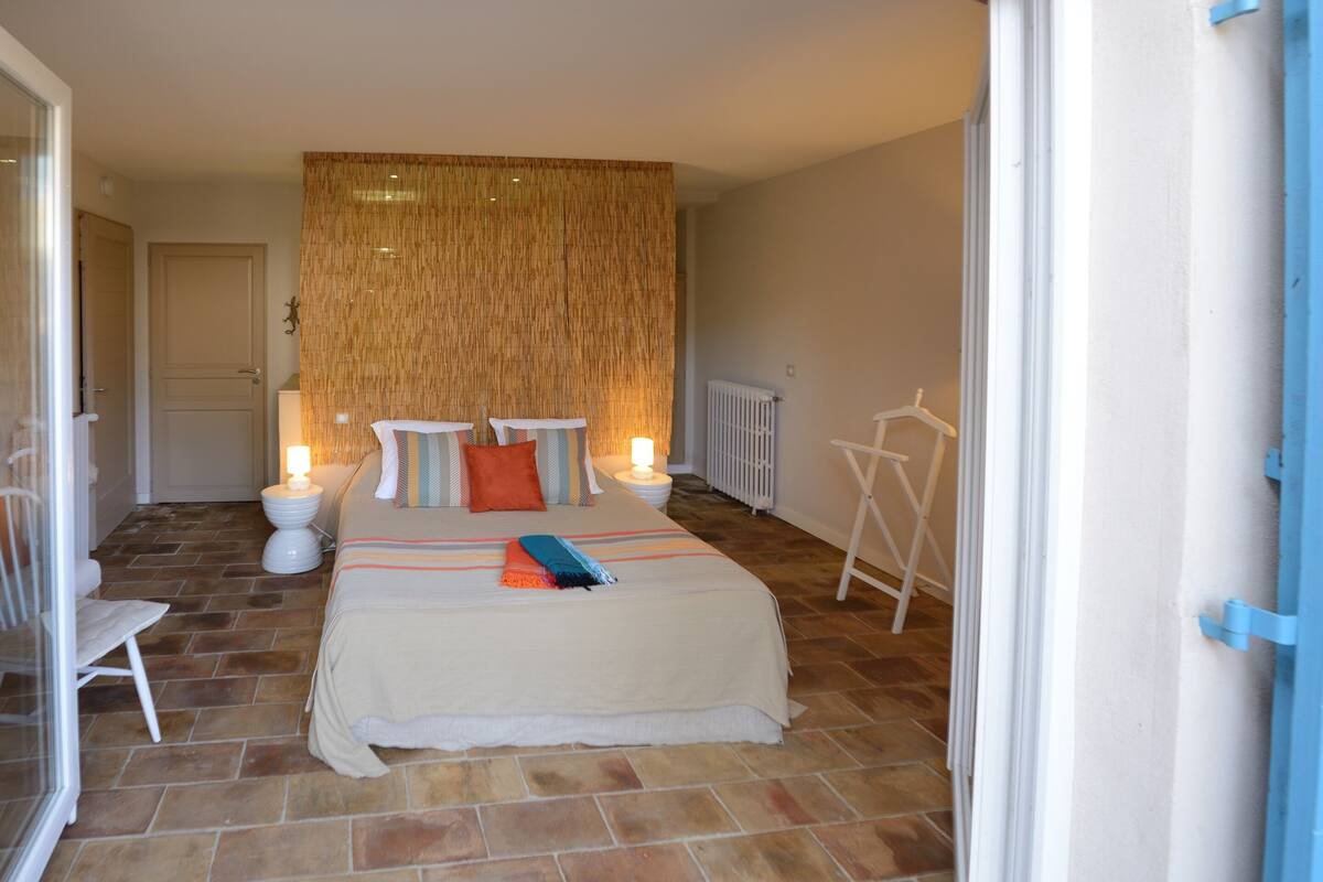 A bedroom with a bed, bedside lamps, a radiator, and a hanging clothes rack.