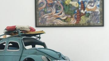 A vintage toy car with a small figure on top, placed in front of a colorful abstract painting.