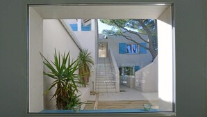A modern building with a staircase leading to a second floor, surrounded by potted plants. - La Singulière (Sète)