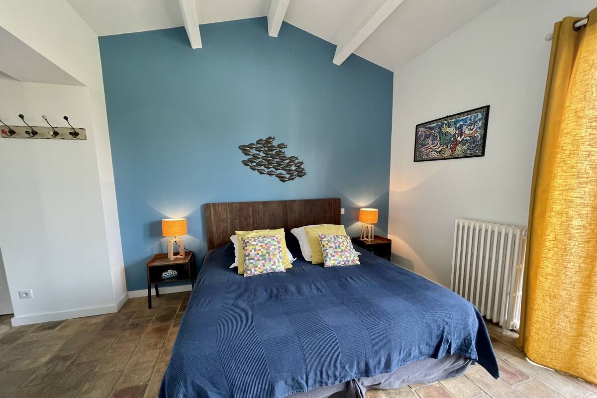 A bedroom with a blue wall, a wooden headboard, two bedside tables with lamps, and a radiator.