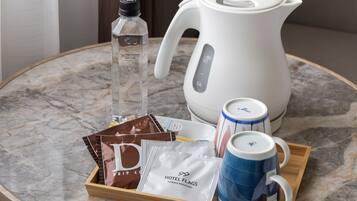 A tray with a coffee maker, a bottle of water, a mug, and some packaged food items on a marble table.