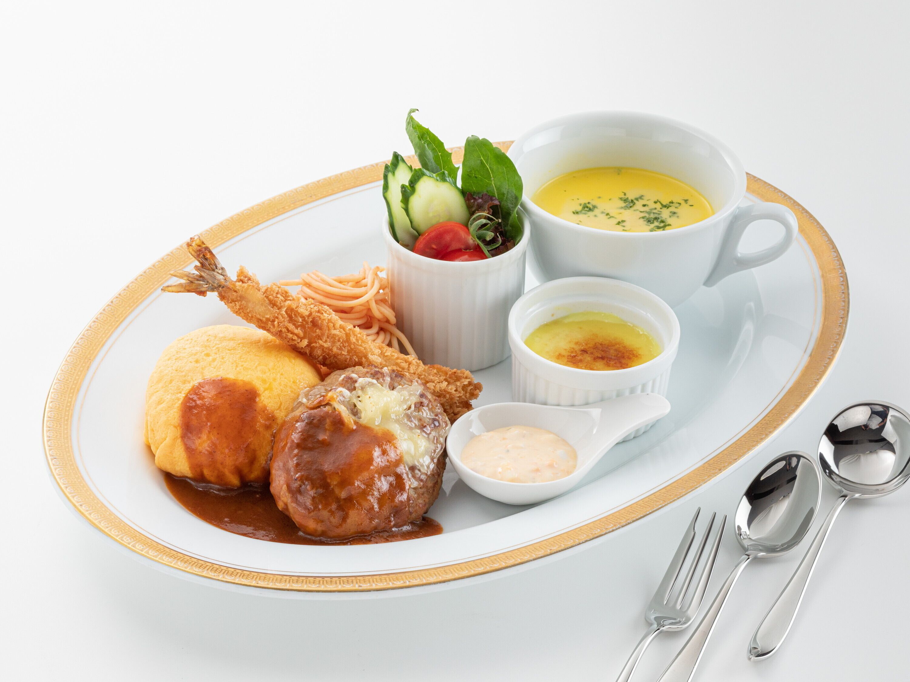 A plate with a variety of dishes including fried fish, a meatball, a dumpling, and a salad, along with two small bowls of sauce and a cup of soup.