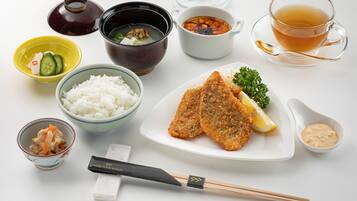 A variety of Japanese dishes including rice, soup, and a fish fillet, along with chopsticks and a teacup.