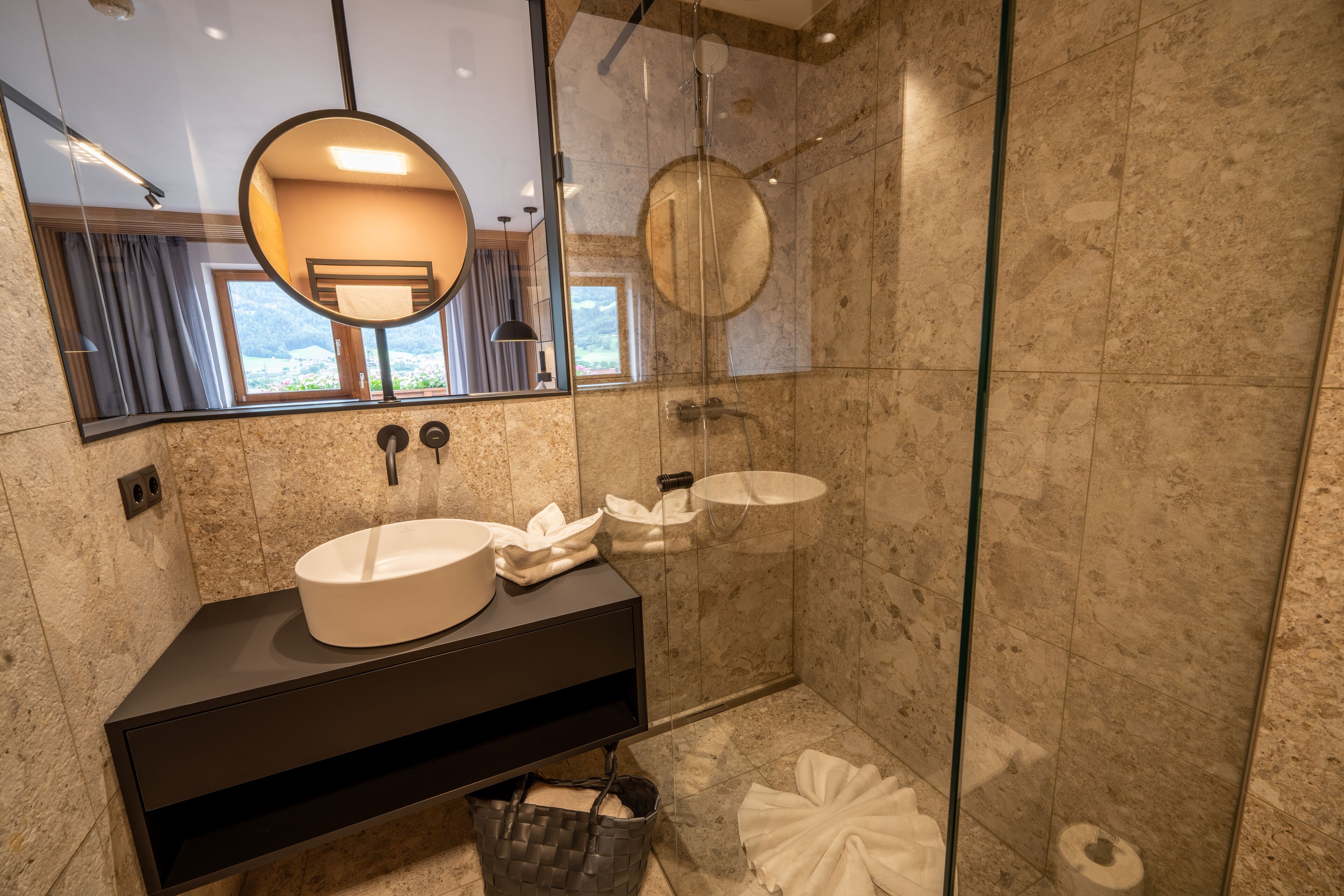 A modern bathroom with a large mirror, two sinks, and a glass-enclosed shower.