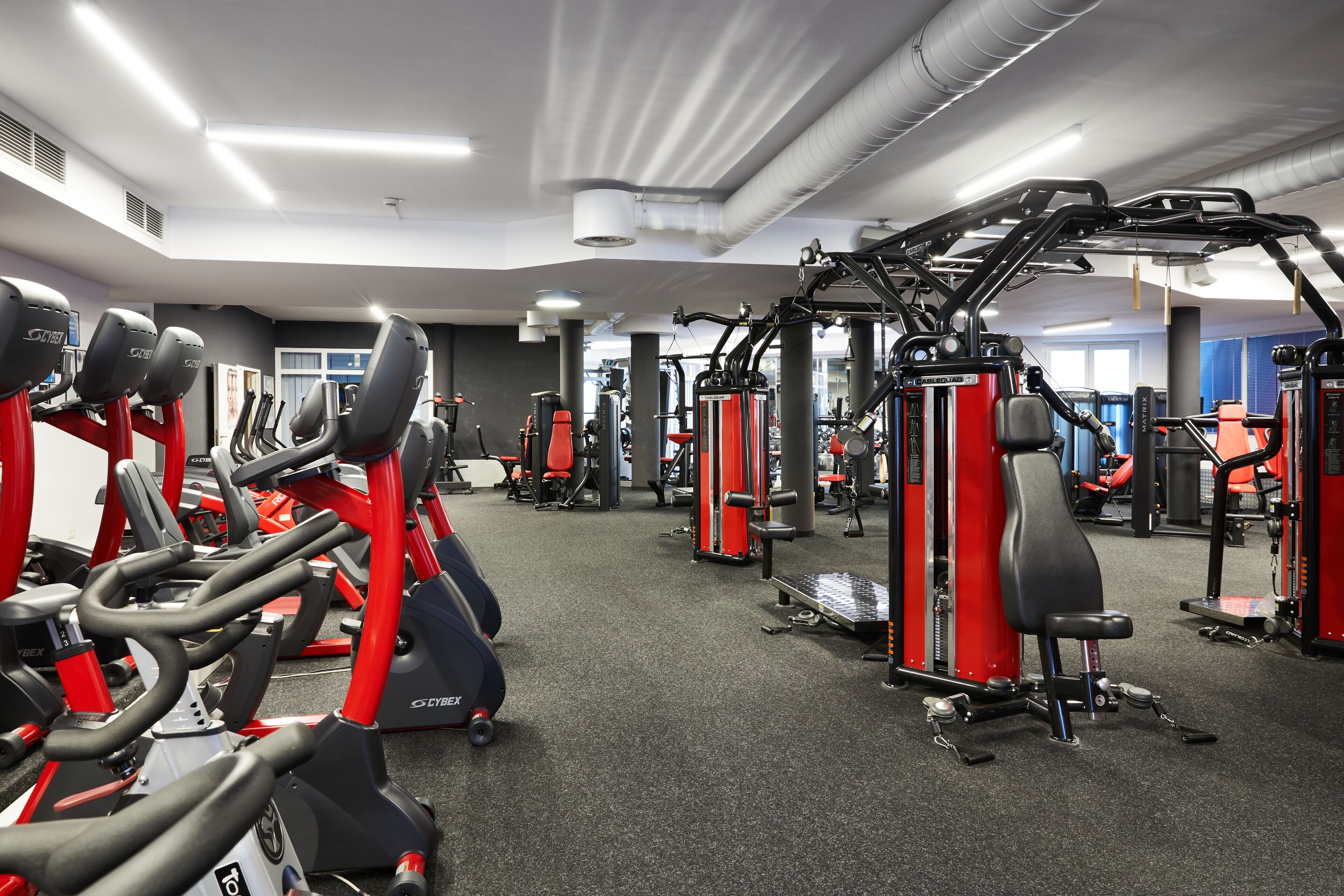 A gym with stationary bikes, weight machines, and a mirror wall.