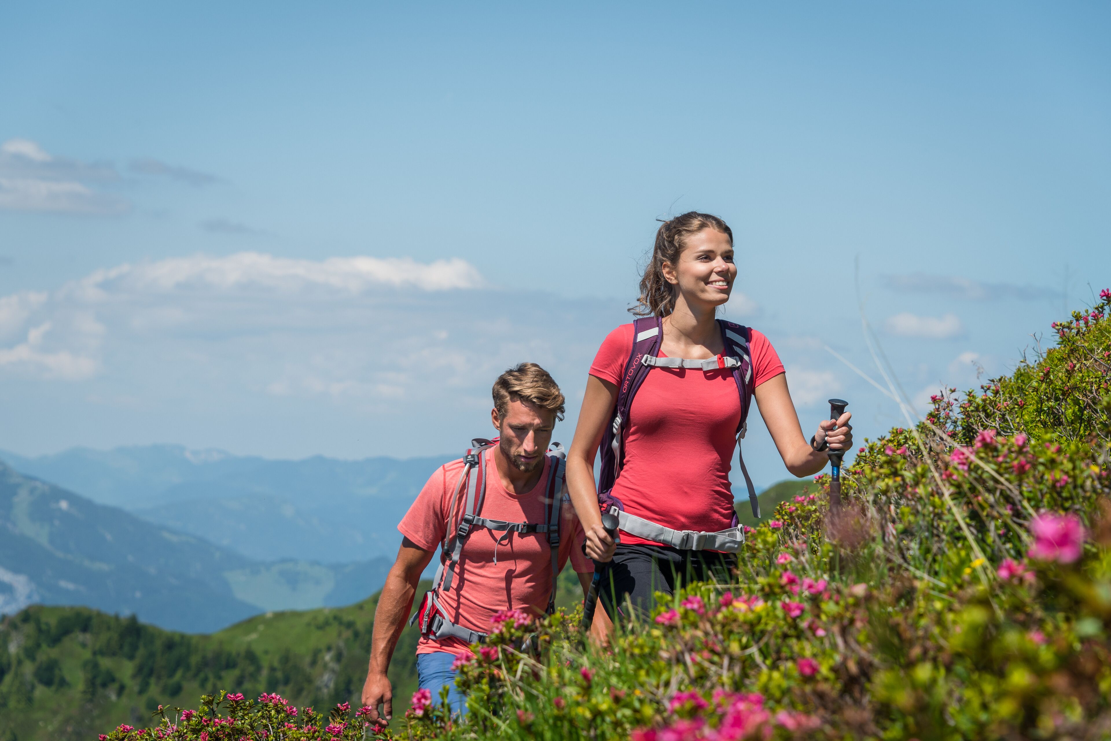 Zwei Wanderer mit Rucksäcken in einer Bergregion unterwegs.