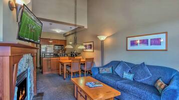 Un salon avec une cheminée, un canapé, une table basse et un téléviseur fixé au mur.