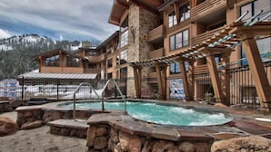 Un chalet doté d’un bain à remous, de murs en pierre et offrant une vue sur une montagne enneigée.