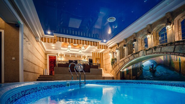 Una piscina interior con techo estrellado, paredes de piedra y un mural de una góndola.