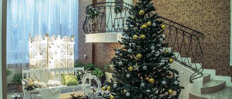 Una imponente escalera con un árbol de Navidad, un banco blanco y un espejo decorativo.