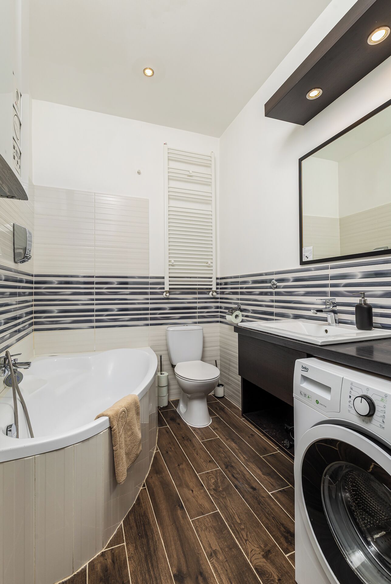 A modern bathroom with a freestanding bathtub, a toilet, a sink with a mirror, and a washing machine.