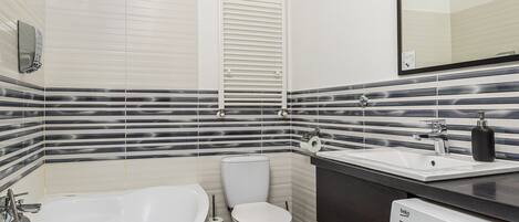 A modern bathroom with a freestanding bathtub, a toilet, a sink with a mirror, and a washing machine.