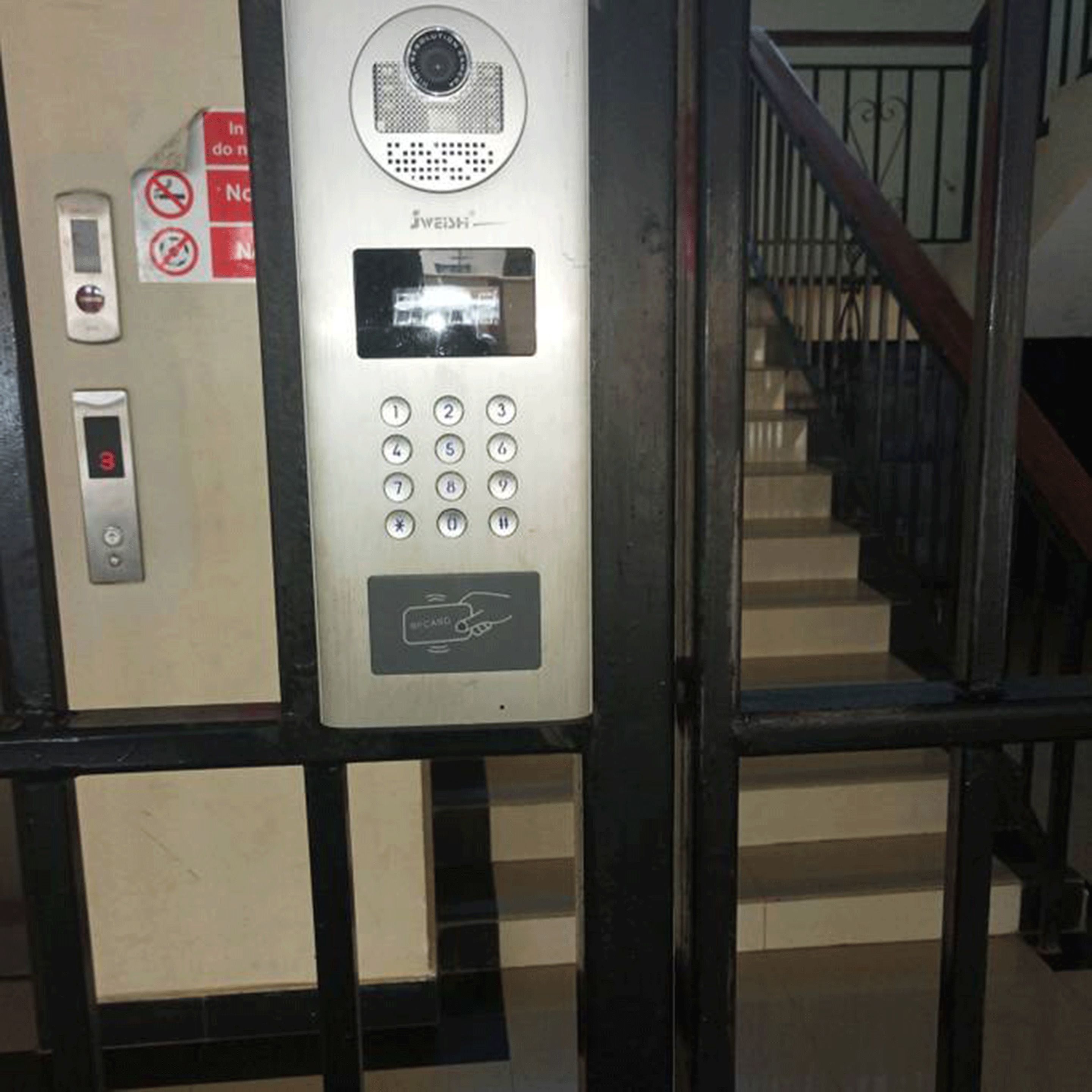 Un clavier de sécurité doté d’une caméra et d’un écran numérique, situé près d’un escalier.