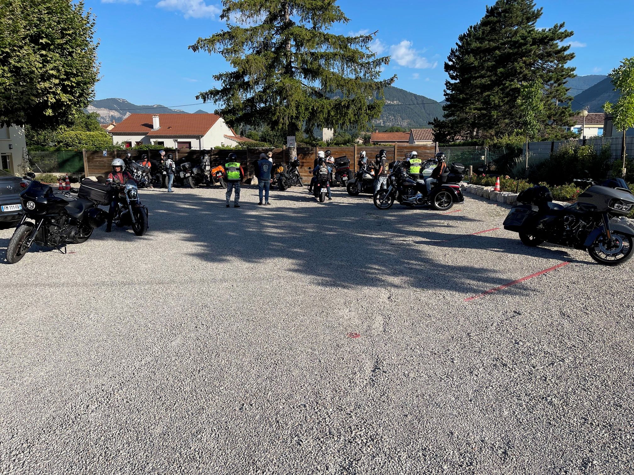 A gravel parking area with multiple motorcycles parked.