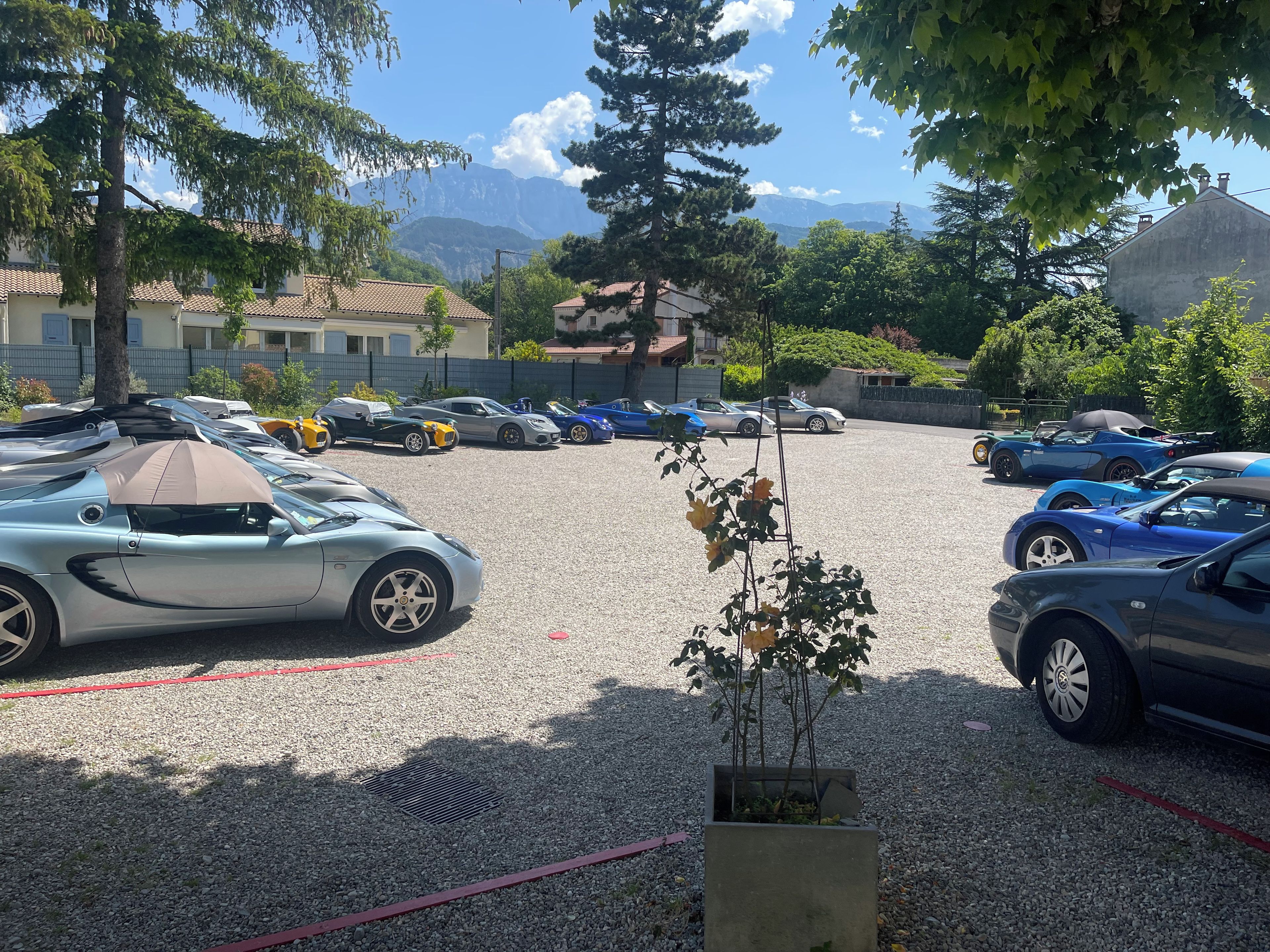 Un estacionamiento con varios autos deportivos y un edificio con techo de tejas al fondo.