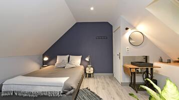 Ein Schlafzimmer mit Bett, Nachttischen, einem Spiegel, einem kleinen Waschbecken und einer Pflanze.
