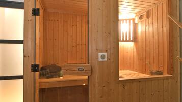 Een houten sauna met een bankje, een klein plankje en een raam.