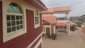Un edificio de varios pisos con fachada de ladrillo rojo y detalles blancos, que presenta ventanas en arco y un patio cubierto.