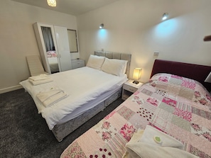 A bedroom with a bed, a nightstand, a wardrobe, and a mirror.