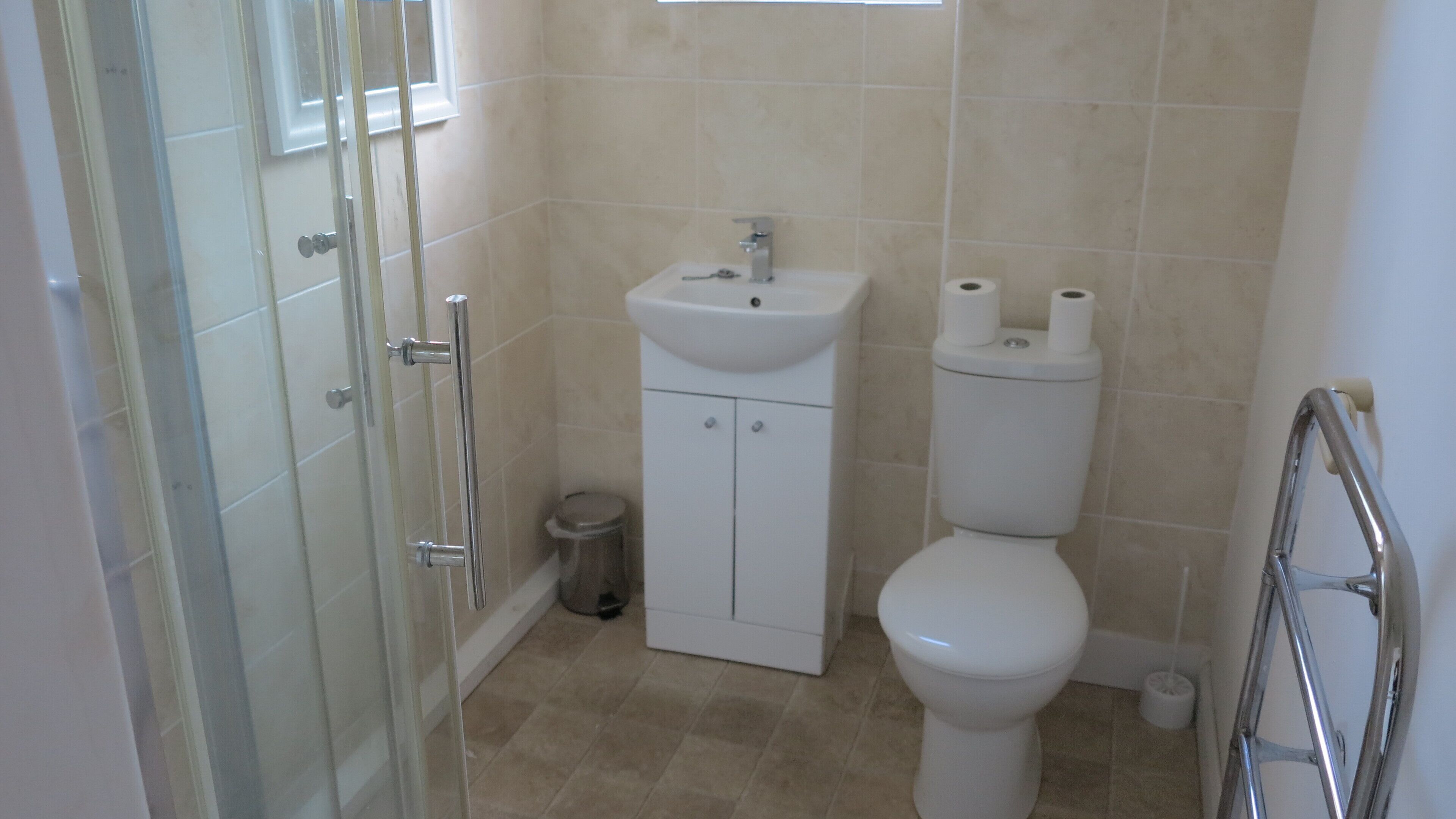 Een badkamer met toilet, wastafel en een douchecabine van glas.