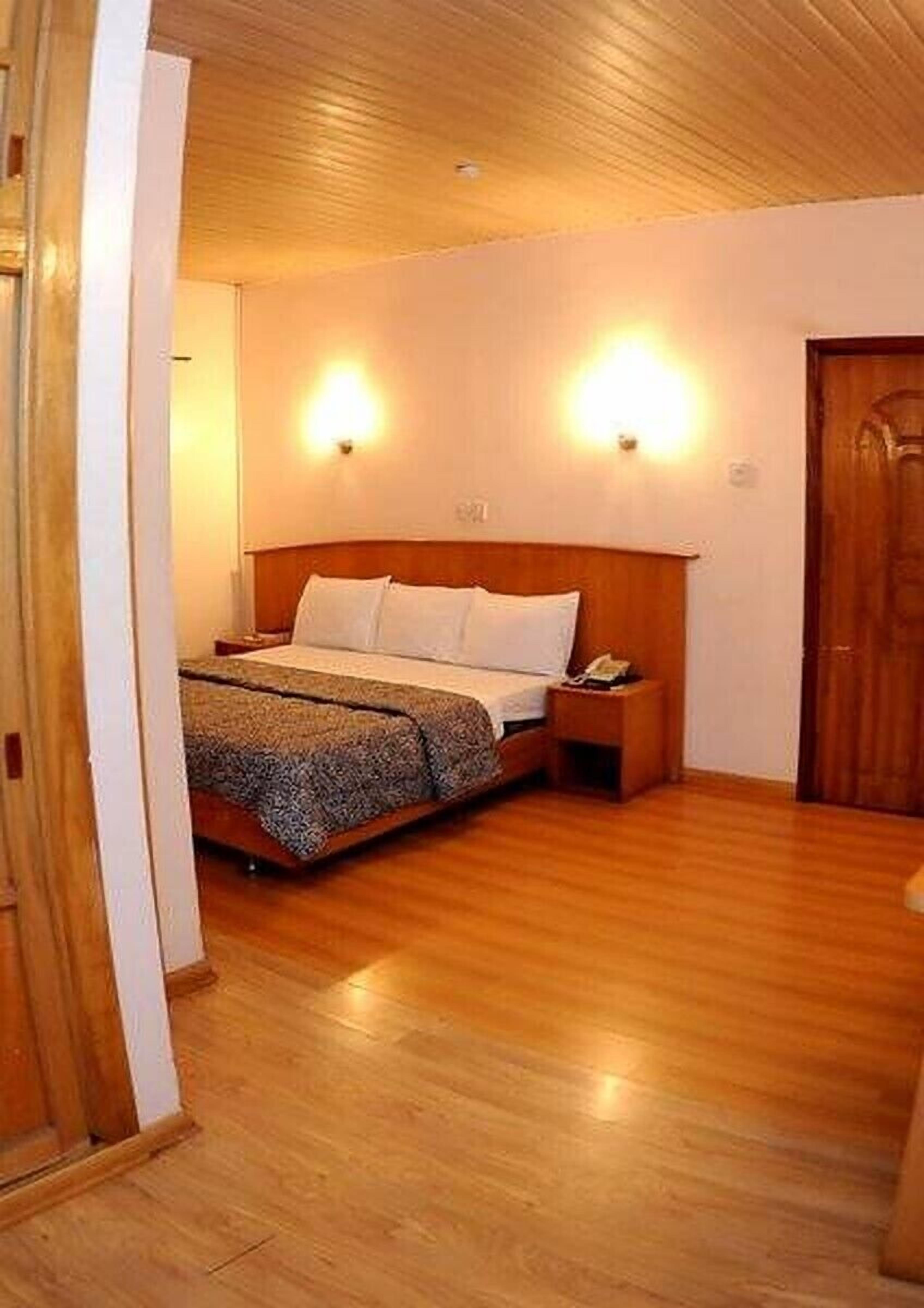 Une chambre à coucher avec un lit en bois, deux tables de chevet et des lampes fixées au mur.