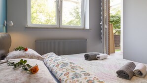 A bedroom with a bed, a radiator, and a window with an open door. - Apartament Praga Tower (Warsaw)