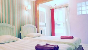 Une chambre d’hôtel avec un lit, des oreillers, un rideau rouge et une fenêtre donnant sur un paysage.