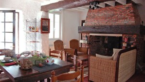 Un coin repas chaleureux avec une cheminée en briques, des meubles en bois et une vue sur l’extérieur.
