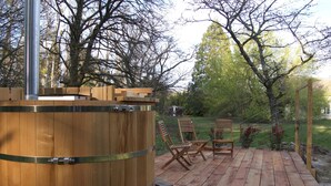Une terrasse en bois avec un jacuzzi, des chaises en bois et une pergola.