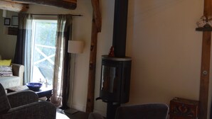 A rustic interior with a loft bedroom, a fireplace, and a dining area with a view.