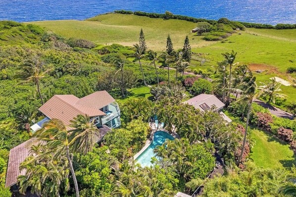 Un resort tropical con piscina, exuberante vegetación y vista al océano.