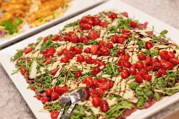 A buffet with a variety of dishes, including a salad with cherry tomatoes and cheese. - Activehotel Diana (Castelrotto)