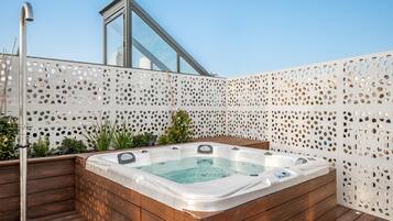 Relax in a serene hot tub surrounded by lush greenery and a deck.