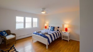 Une chambre à coucher avec un lit, deux tables de chevet, une chaise et une fenêtre.