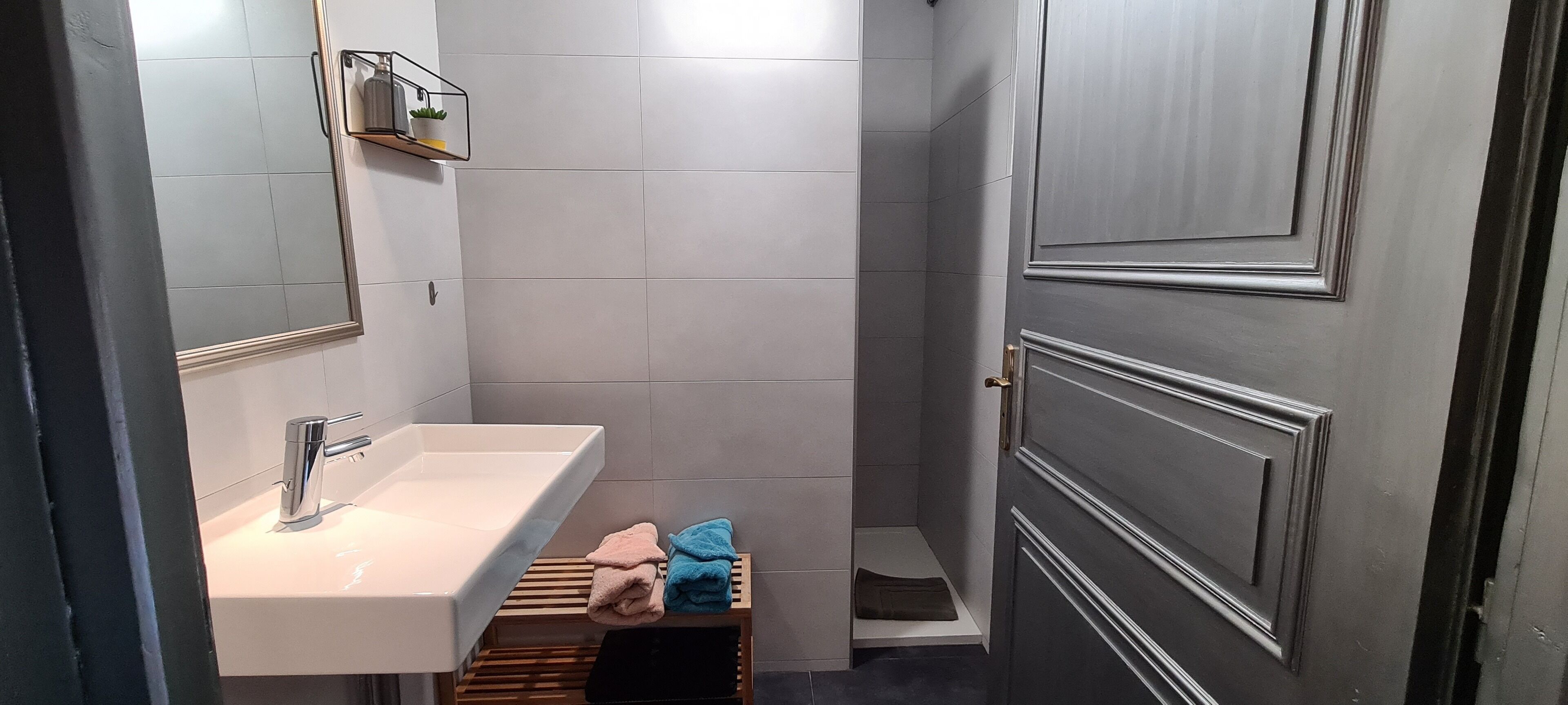 A bathroom with a white sink, a mirror, a towel rack, and a shower area.